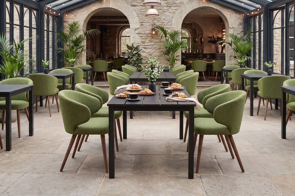 Green boucle upholstered dining chairs around black tables in a conservatory restaaurant
