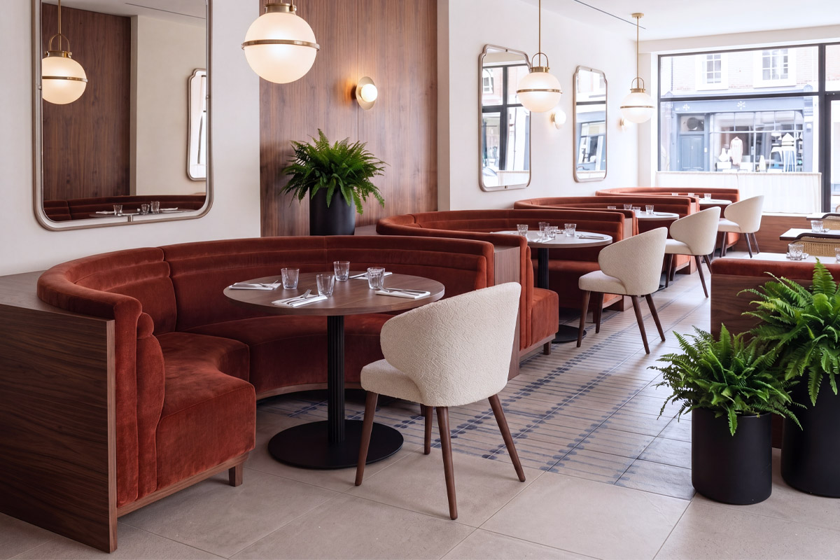 Curved velvet booth seating and upholstered boucle dining chairs